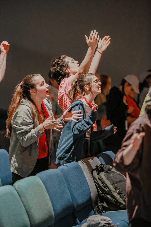 three girls raising hands in worship